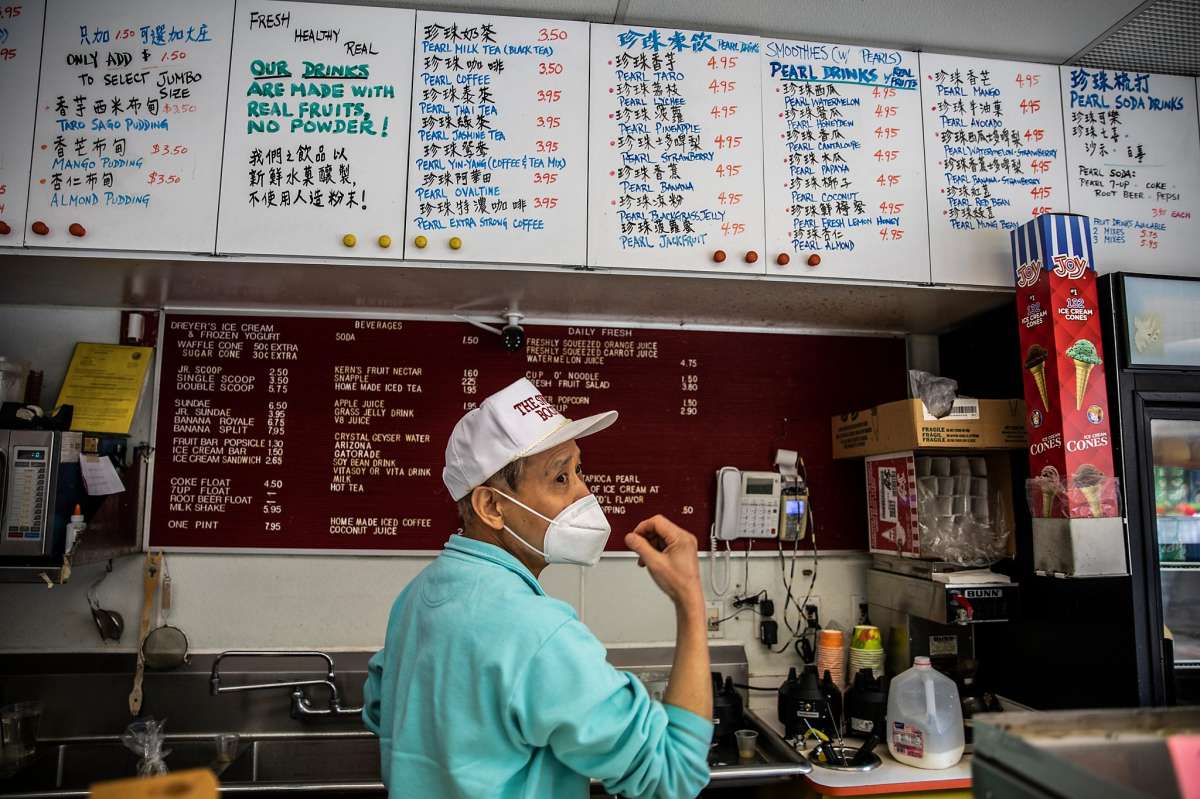 Calvin Tong, owner of The Sweet Booth in Pacific Renaissance Plaza since 1993, looks on while fulfilling a drink order in Oakland, California Tuesday, Feb. 16, 2021. Community members are on heightened alert after the recent increase in violent crimes, many caught on camera, toward the Asian American community throughout the Bay Area. Despite an increased police presence, armed private security, and volunteer groups patrolling the area around Oakland Chinatown, many businesses continue to worry and are taking extra precautionary measures such as boarding up storefronts and closing hours earlier despite how the pandemic-driven economic downturn has already impacted many.