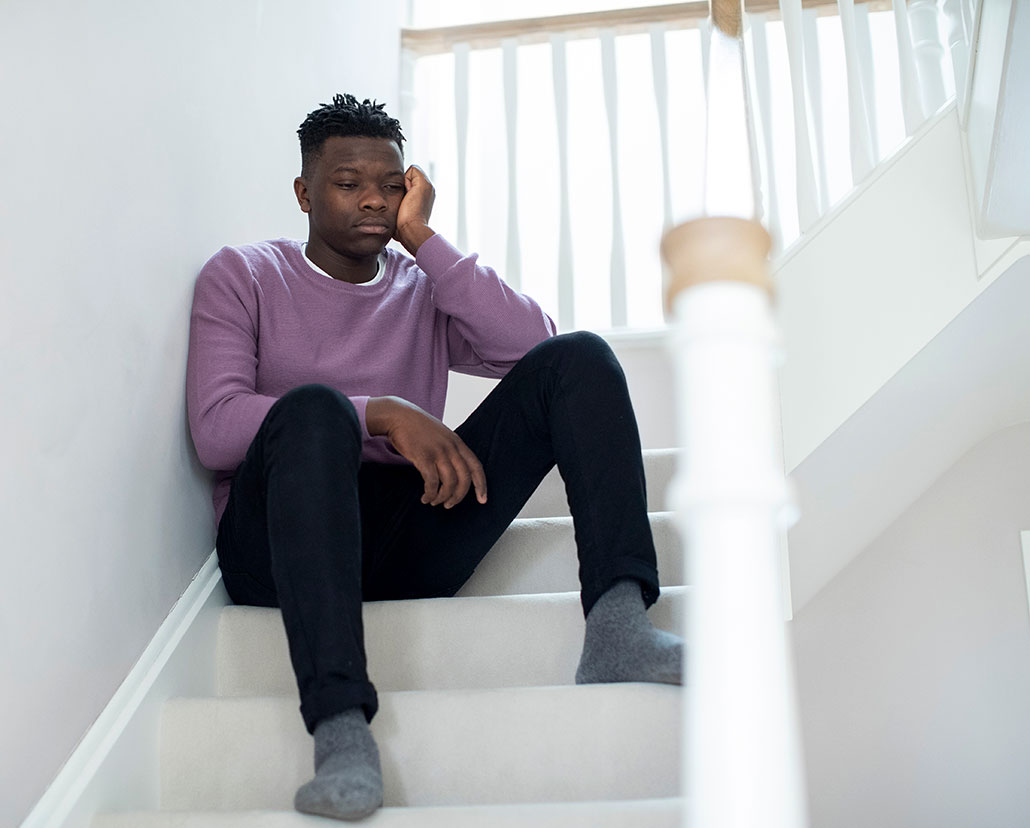 a young Black teen sits on stairs and stares into space