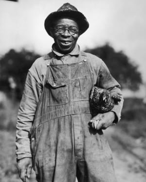 A  farmer with a chicken, circa 1925.