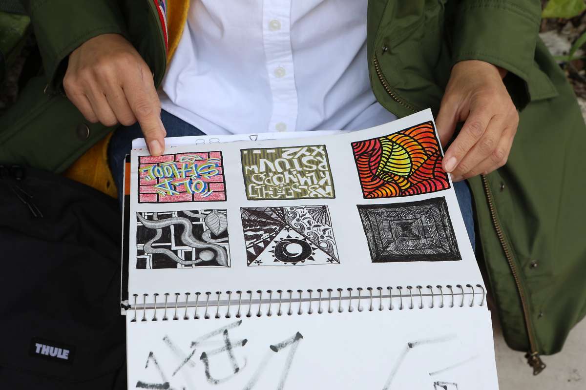 Art teacher Bibi Marti looks at a student's sketchbook at Thurgood Marshall High School on Wednesday, March 17, 2021, in San Francisco, Calif. Teachers meet with students outside the school on Wednesdays to provide them with a range of support.
