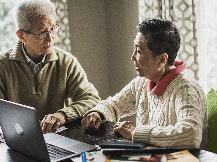 two older adults talk while using a computer